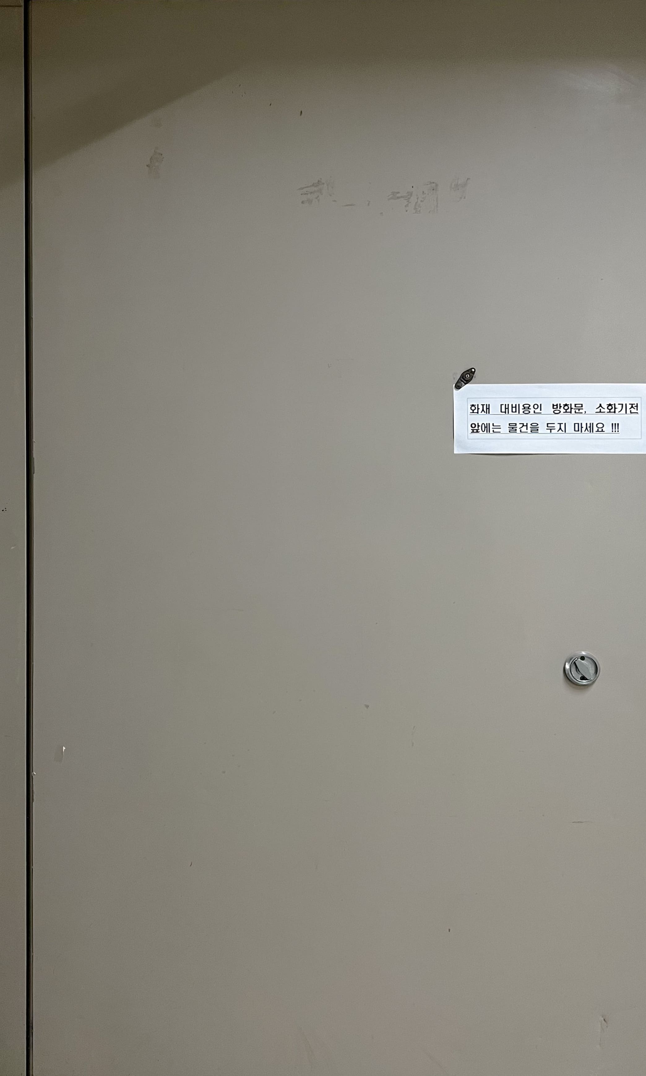 회색빛이 도는 연한 베이지색의 철제로 된 방화문이다.