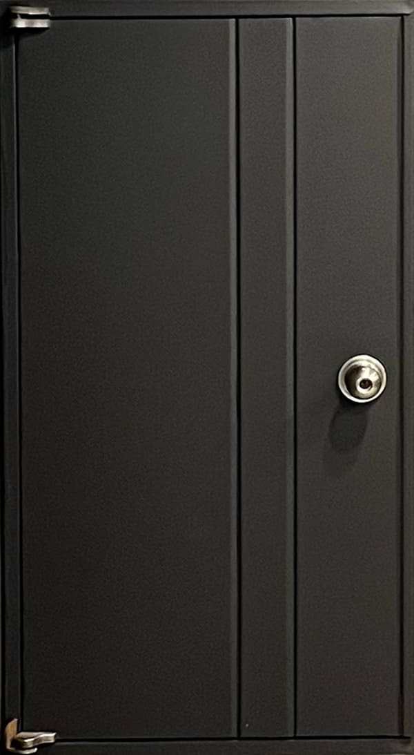 검은색 시트지가 붙어있고 동그란 은색 손잡이가 달려있는 복합재료문이다.