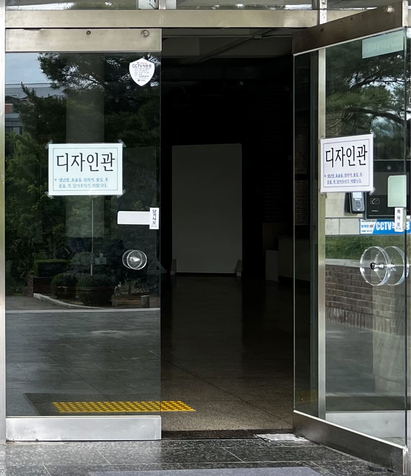 디자인관이라는 글자가 붙은 투명문이다. 왼쪽 문은 닫혀있고 오른쪽 문은 열려있다.
