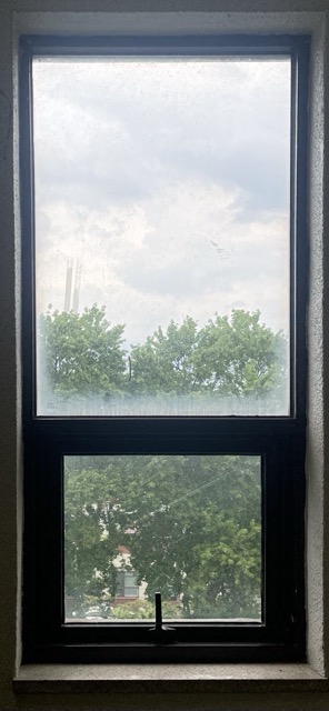 세로로 긴 형태의 검은색 철제 프레임 창문으로 안쪽으로 기울어 여는 방식의 틸트 창문 사진