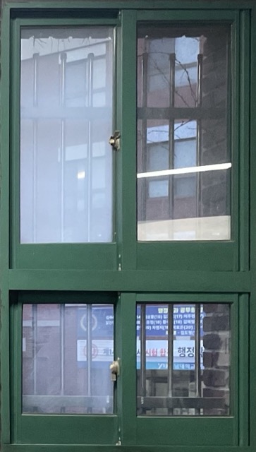 초록색 철제 프레임과 옆으로 밀어서 여는 슬라이드 창문으로 세로로 긴 형태의 4개의 창이 보이는 사진