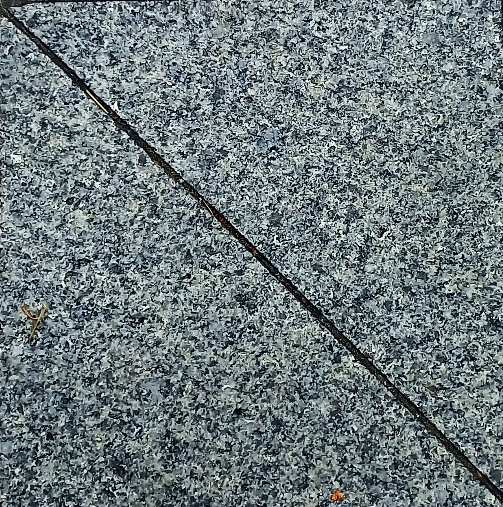 회색 바탕에 작은 검정 반점들이 있는 화강암. 얇은 대각선이 왼쪽 위와 오른쪽 아래를 이어진다.