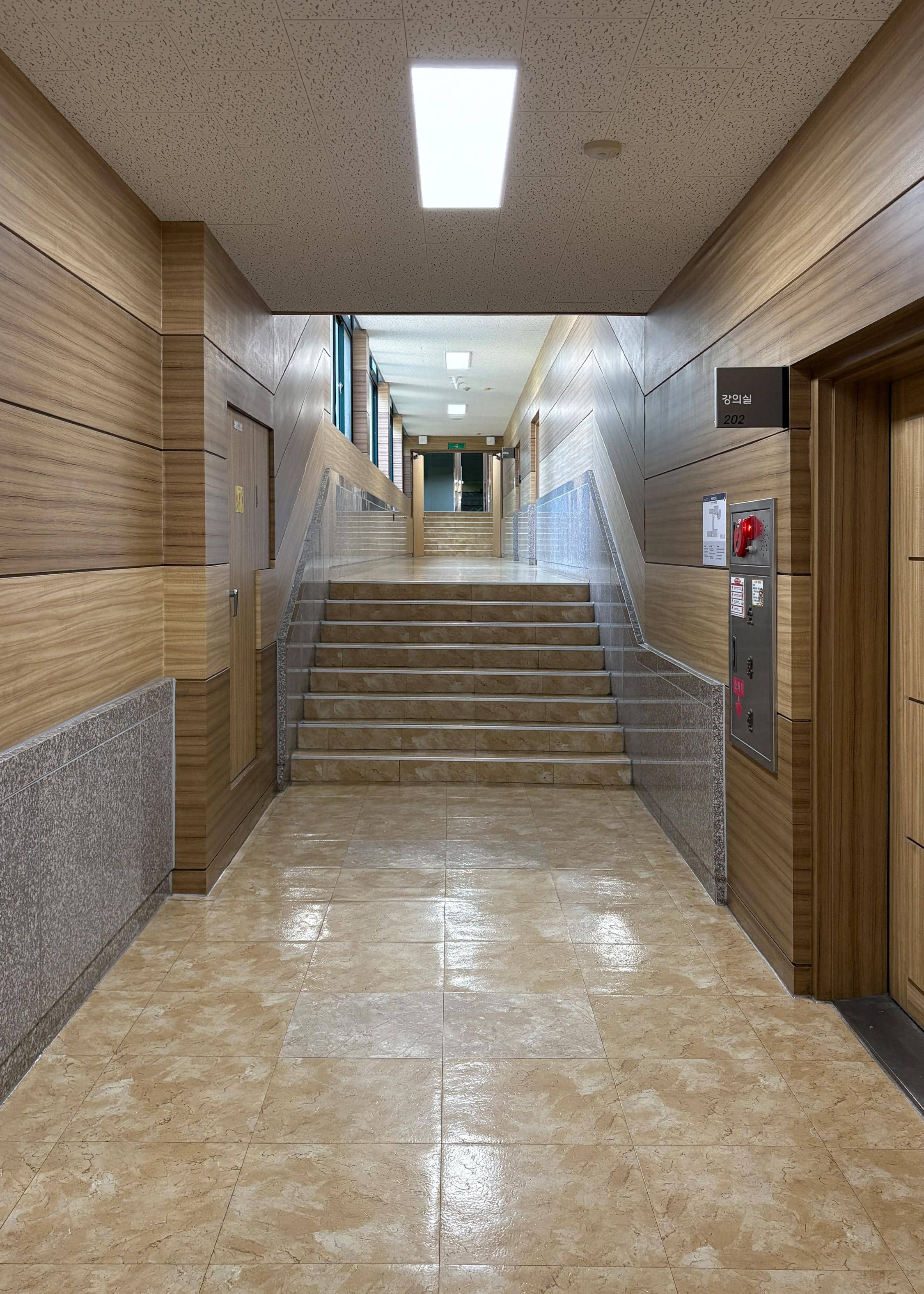 영남대학교 인문관 2층 중복도. 중앙에는 계단이 있다. 오른쪽 벽엔 202호 강의실이 하나 있고 강의실 바로 옆엔 소화전이 있다. 왼쪽 벽에는 파랑색으로 된 창문이 이어져 있다. 복도 끝에는 다른 강의실로 가는 문이 있다. 