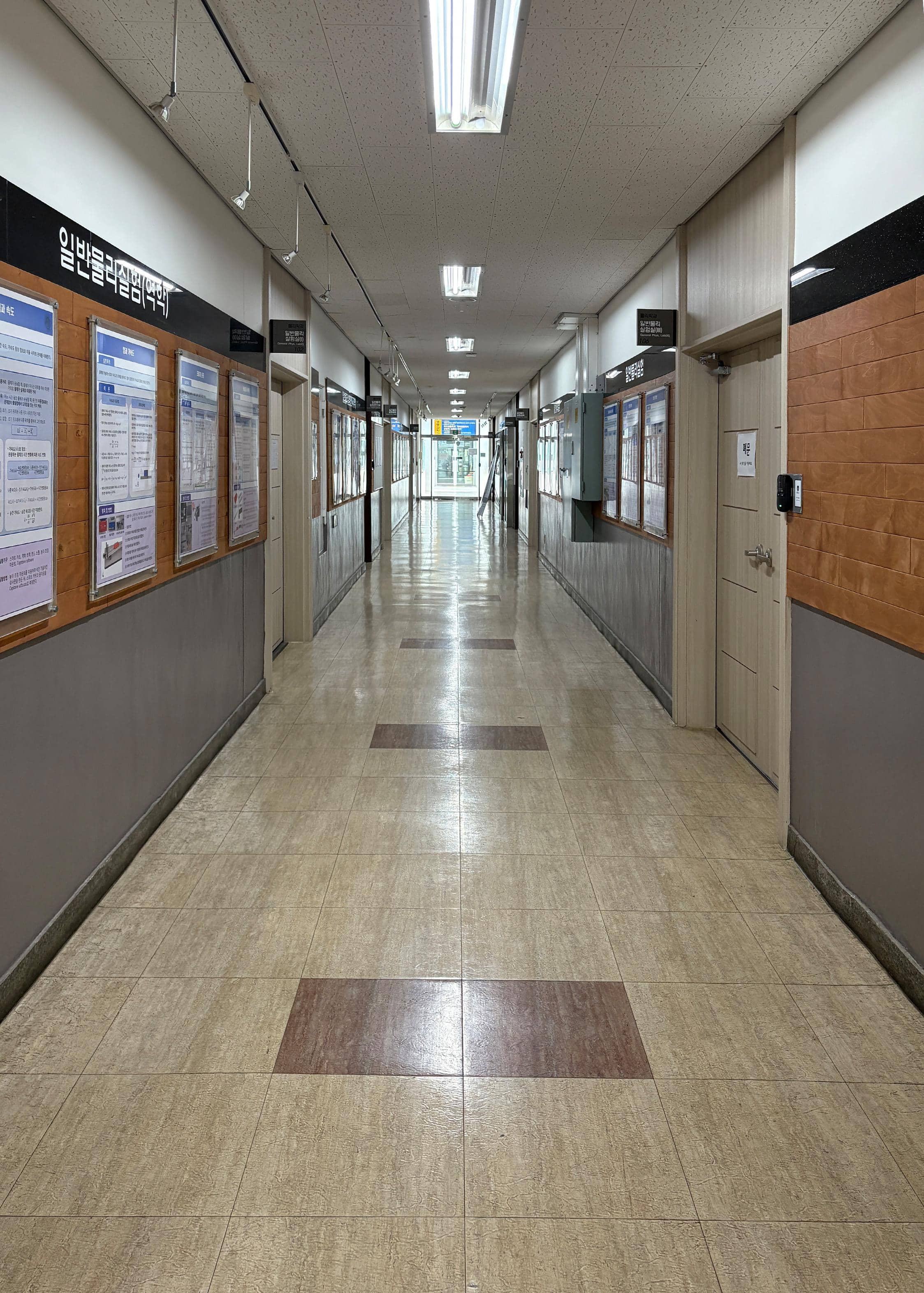 영남대학교 사회과학관 1층 중복도. 왼쪽 벽에는 게시판이 있고 바로 옆에는 실험실들이 있다. 오른쪽 벽에는 또다른 실험실들이 있다. 복도 끝에는 다른 건물로 이동할 수 있는 유리문이 있다.