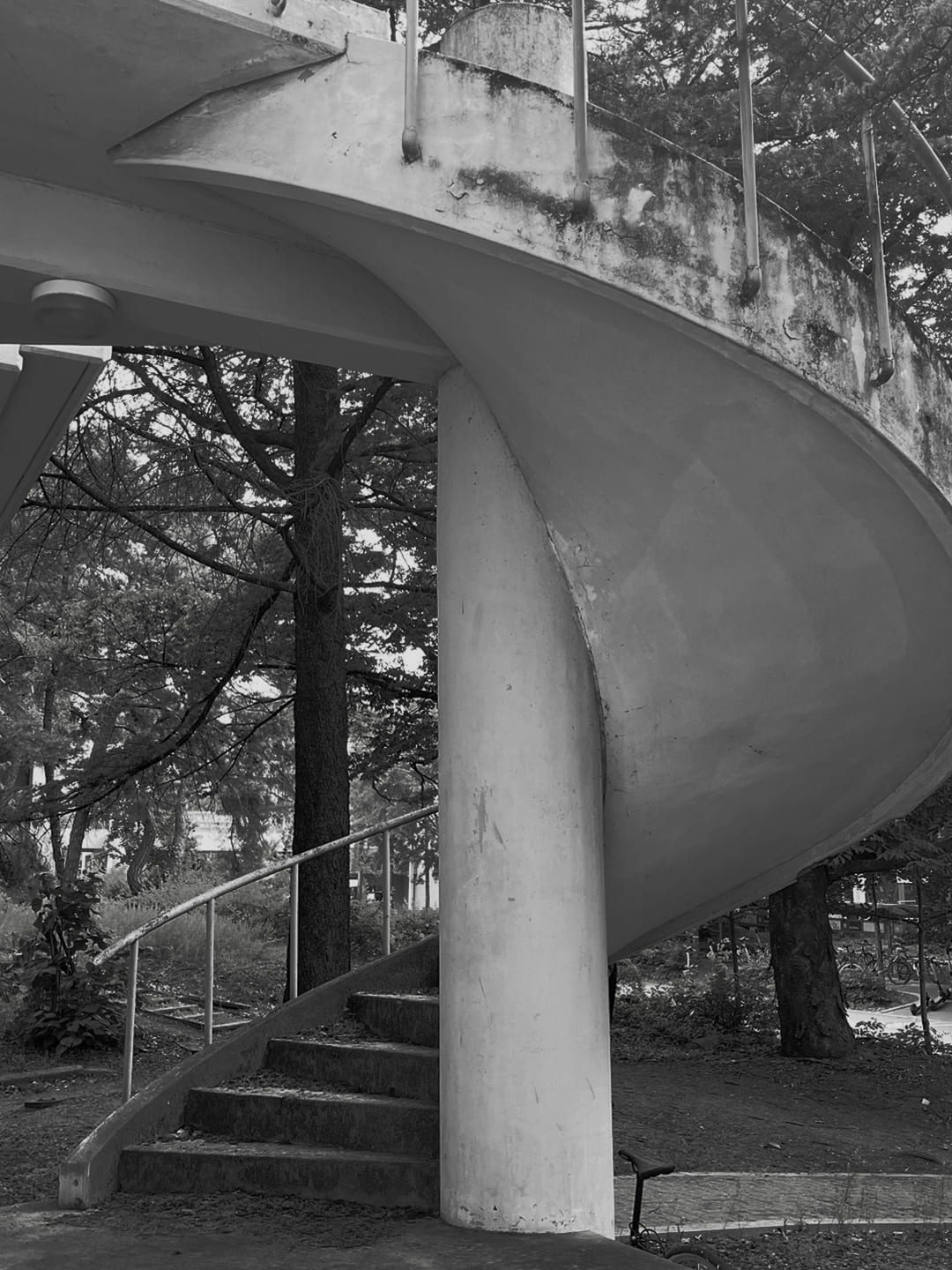 흰색 기둥을 가준으로 돌아가는 탁한 갈색 타일의 나선형 단을 옆에서 찍은 사진.