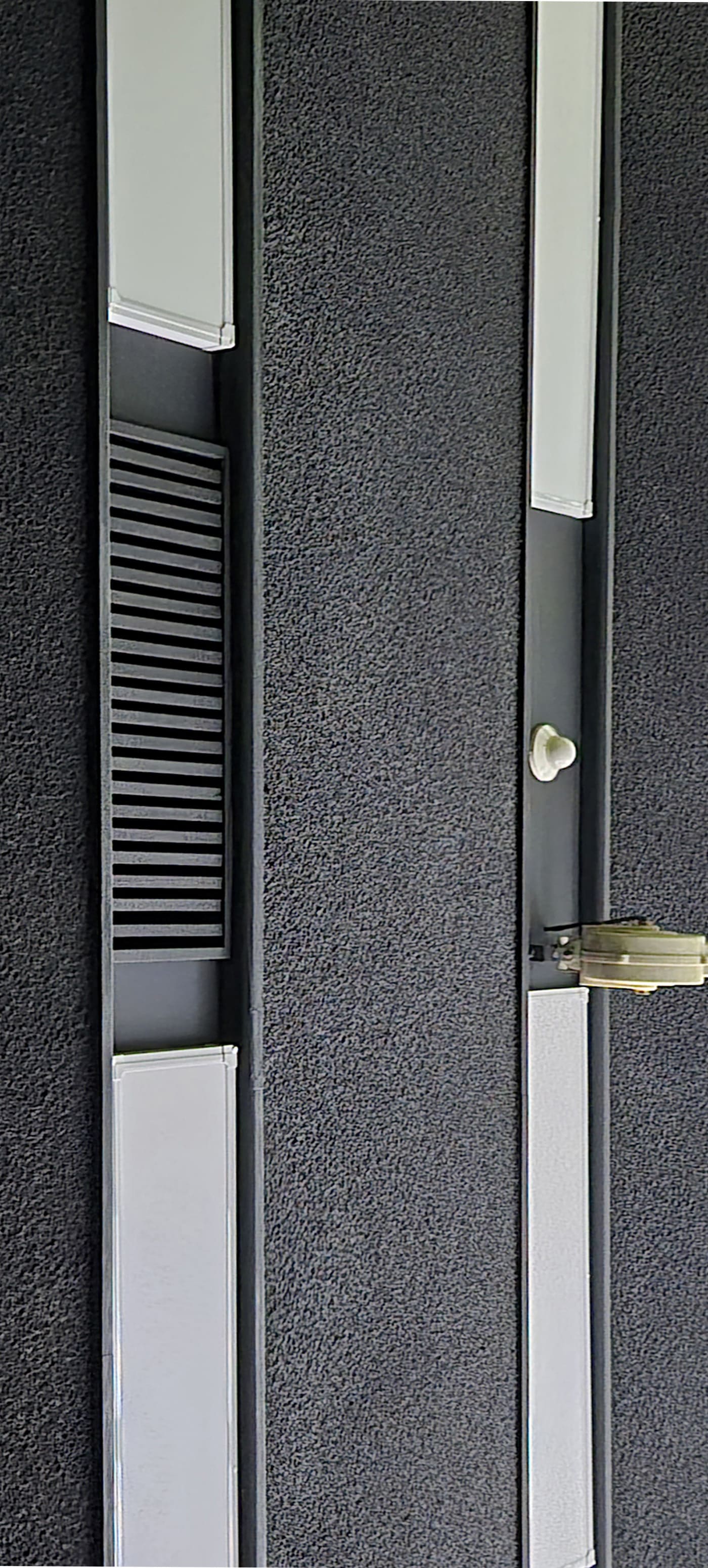 검은색 배경의 천장 사이 길쭉한 조명이 규칙적으로 배치된 형태의 천장 사진이다. 천장의 표면은 약간 까끌한 질감처럼 보인다 천장의 조명이 세로로 찍힌 사진이다.