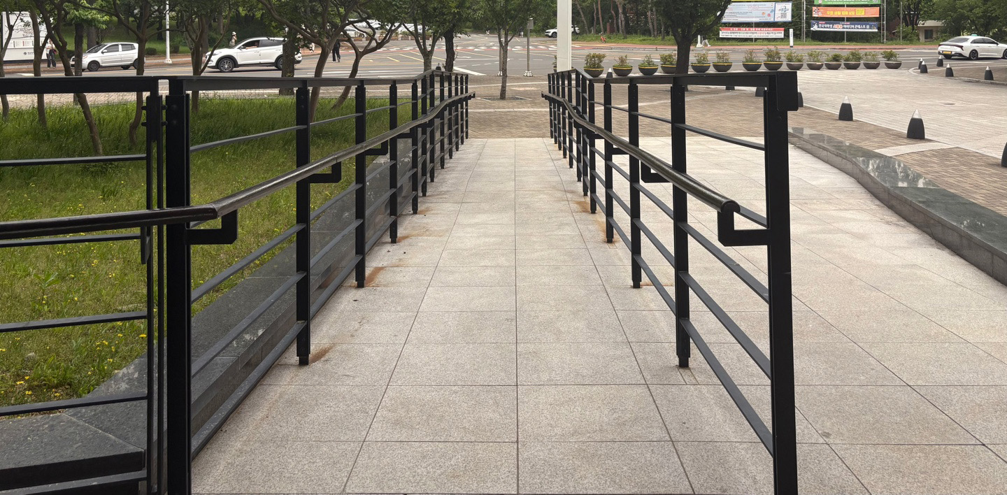 직선형의 검은색 손잡이,아이보리 색 바닥이고 중간 지점에 수평으로 착지가 가능한 공간이 있는 램프의 정면 사진입니다