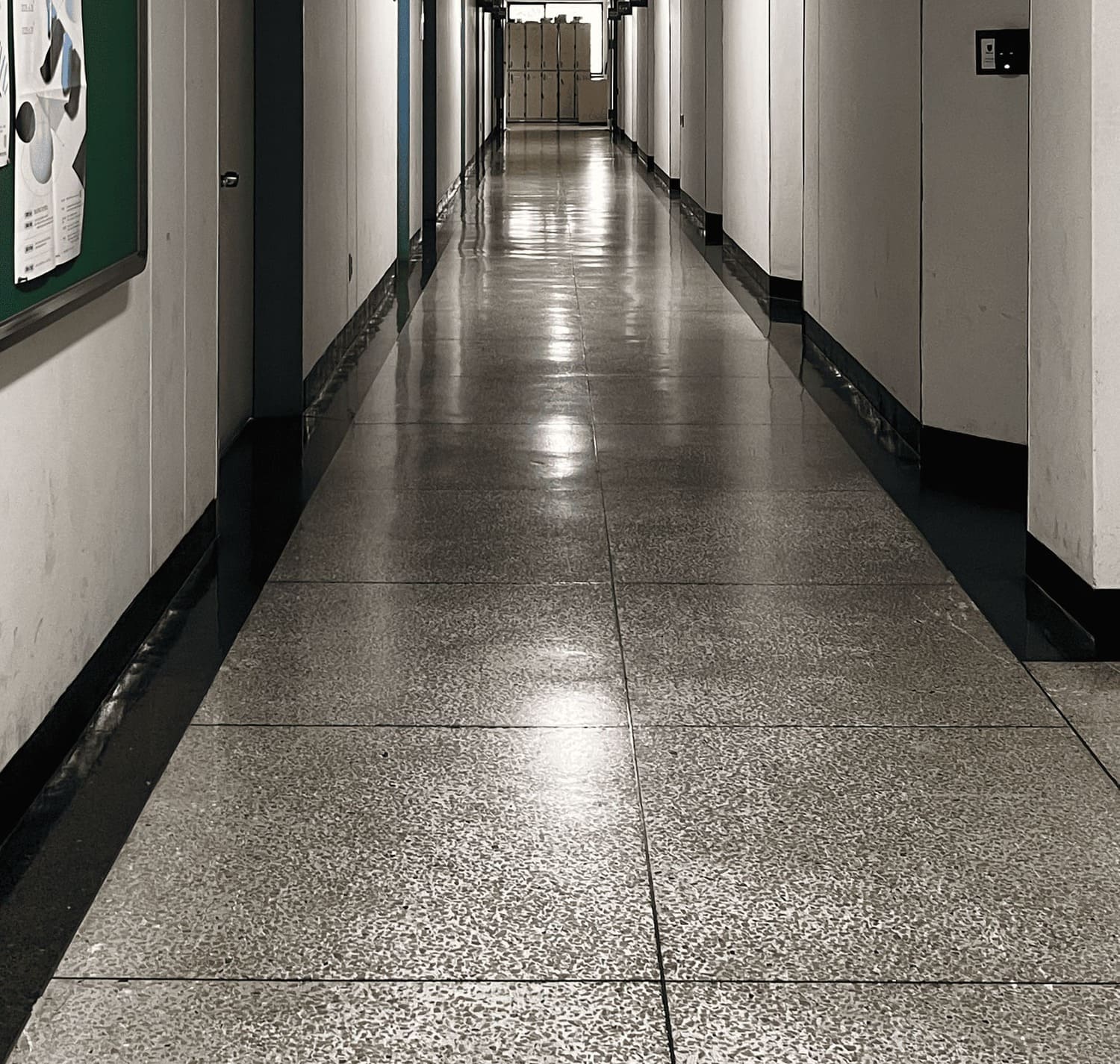 소실점이 중앙에 있는 복도의 중간부터 바닥까지의 사진. 왼쪽 벽에는 철제로 된 문이 있고 먼 곳에 몇 개의 문틀이 더 보인다. 왼 편에는 벽 중간중간 오목한 부분이 있다. 바닥엔 큰 테라조 타일이 쭉 나열되어있다.1번 복도의 아래
