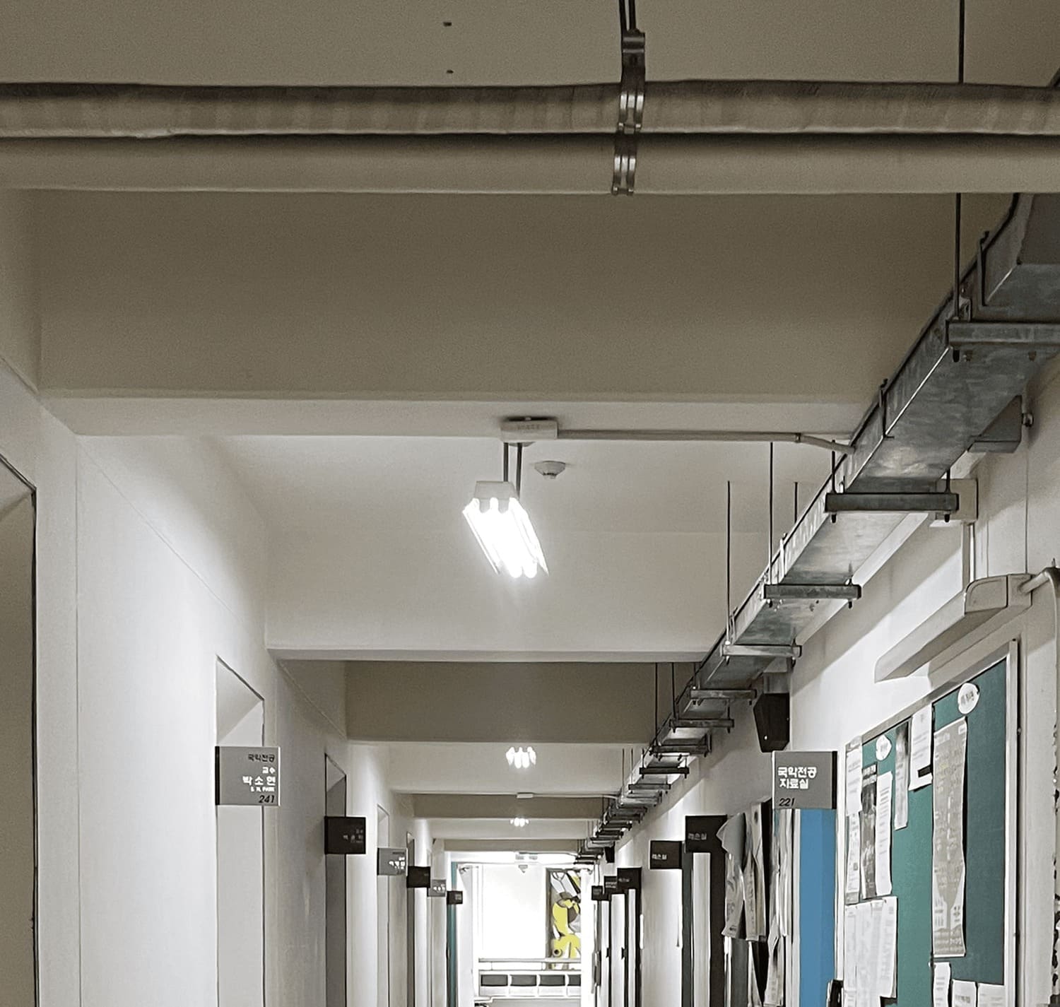 소실점이 중앙에 있는 복도의 중간부터 천장까지의 사진. 왼쪽 벽에는 교수 연구실이 여러개 있으며 입구가 오목하게 들어가있다. 오른쪽 벽에는 국악전공 자료실을 비롯한 방들이 멀리에 위치하고있다. 천장에는 규칙적으로 보가 튀어나와있다. 보가 없는 들어간 부분엔 두 칸에 하나씩 노출형 형광등 2구가 매달려있다. 천장의 왼쪽 끝에는 덕트가 설치되어있으며 사진의 가장 위쪽에는 노출형 배관 2개가 가로로 설치되어있다. 3번 복도의 위.