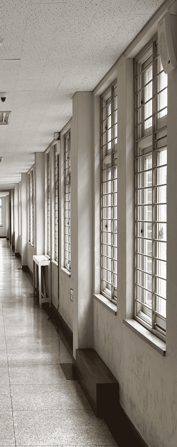 중앙에 소실점이 위치한 채 찍힌 사진의 중앙부터 왼편까지의 절반. 흰색 벽 아래는 발자국 흔적이 남아있다. 벽의 거의 맨 위에서부터 80%까지 오는 커다란 창이 쭉 나열되어있다. 창에는 가로로 된 금속 창살이 15개씩 설치되어있다. 복도 중간쯤 되는 거리에는 벽에 딱 붙어있는 하얀색의 직사각형 탁자가 있다.