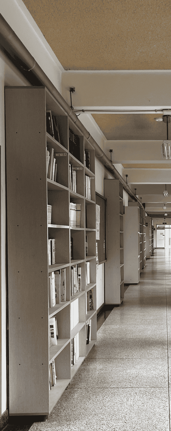 중앙에 소실점이 위치한 채 찍힌 사진의 중앙부터 왼편까지의 절반. 왼쪽 벽에는 사물함이 띄엄띄엄 배치되어있다. 가장 가까운 두 서랍장 사이에는 게시판이 있다. 서랍장 위 천장에는 긴 덕트가 설치되어있다. 전체적으로 회색빛이 도는 사진, 황토색 천장에는 흰색 보가 규칙적으로 내려와있다. 보에는 직사각형 전등이 설치되어있다.