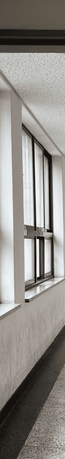 중간에 소실점이 모이는 복도를 세로로 4분할 했을 때의 왼쪽에서 첫번째 사진. 콘크리트 벽에 검은색 알루미늄 창틀, 사각형 창문을 6분할하여 위에 3개는 아래가 긴 직사각형, 아래 3개는 가로로 긴 직사각형이다. 천장은 흡음 패널.