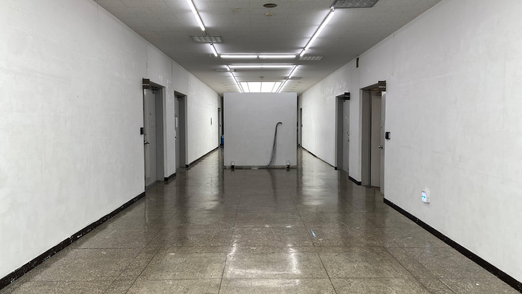 영남대학교 미술관 복도 이미지. 앞에는 흰색 벽이 복도 중앙을 막고있다. 복도 양 옆에는 철제문들이 달려있다.