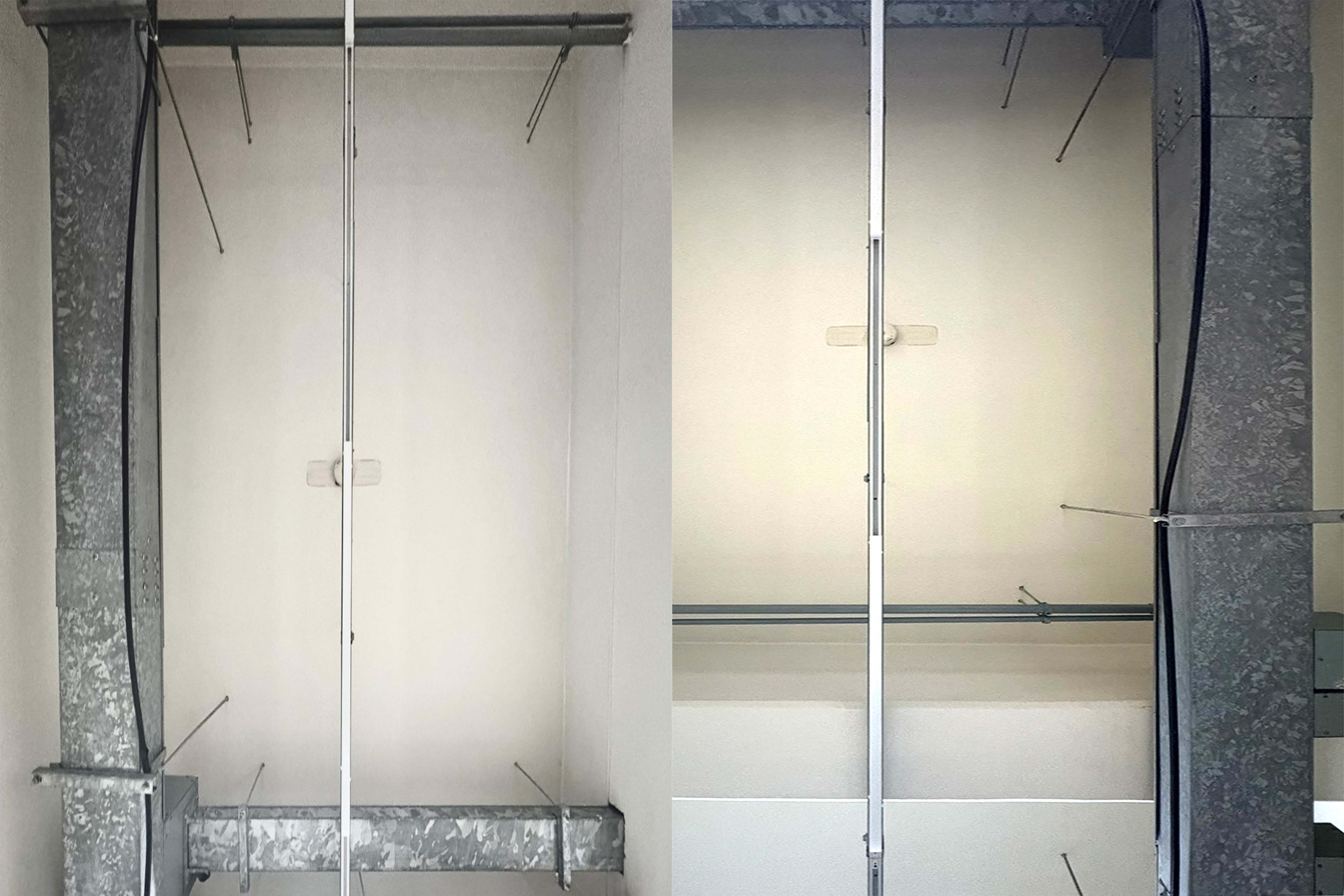 흰색 천장에 세로, 가로 단이 있어 높이 차이가 느껴진다. 긴 직선 배관과 검정색 선이 가로 세로로 길게 뻗어있다. 긴 진회색 금속 직사각형이 수평, 수직으로 이어져 사각형의 모서리처럼 만나는 부분이 있다.