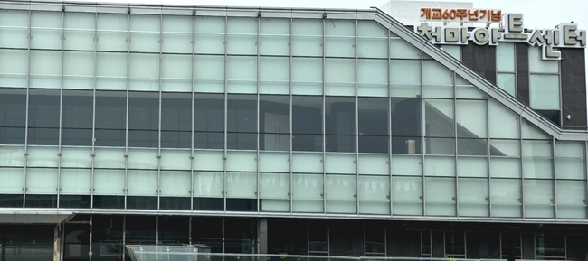 벽 외관 전체가 수직, 수평으로 격자처럼 나뉜 투명한 유리창으로 이루어져 있고 가로로 긴 직사각형 건물이다.