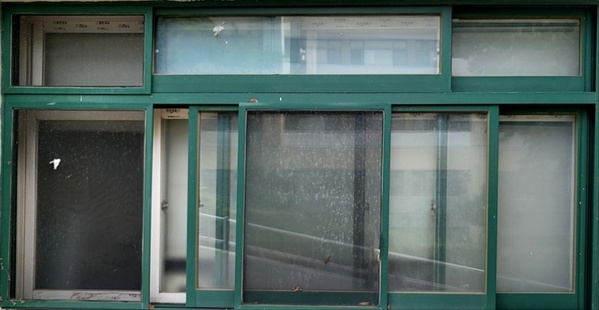 초록색 창틀에 여러 개의 유리창이 겹쳐진 채 열려있는 창문