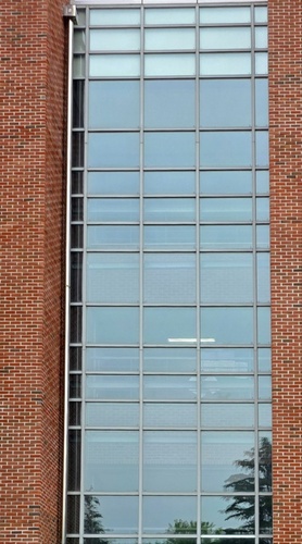 벽의 일부가 유리로 된 세로로 긴 직사각형 형태의 건물이며, 벽 전체가 수직과 수평으로 격자처럼 나뉜 투명한 유리창으로 구성되어 있다.