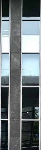 어두운 회색 벽에 세로로 긴 직사각형의 창문 2개가 있으며 왼쪽의 창이 오른쪽 창보다 폭이 좁다.