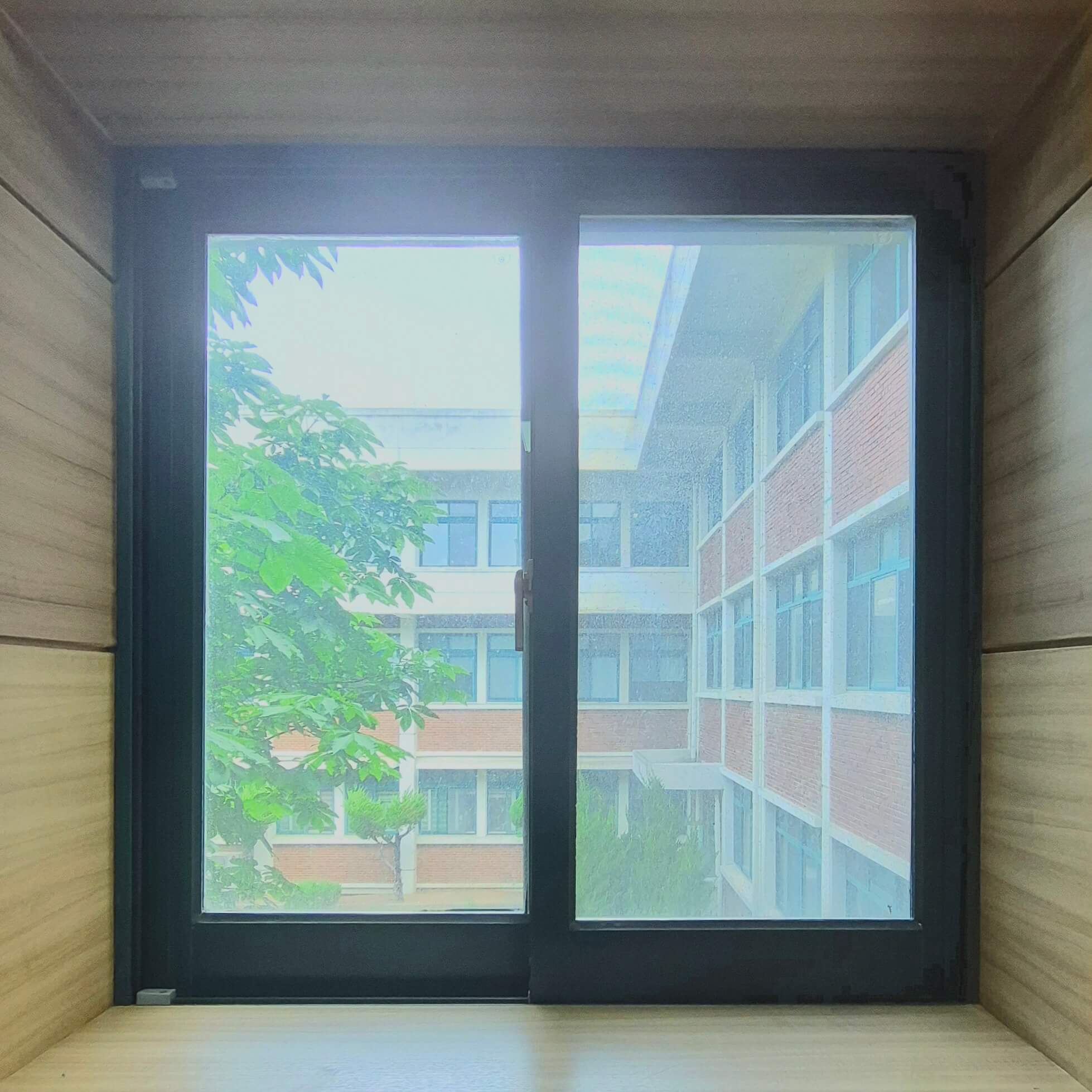 인문관 창문, 나무 재질의 벽 위에 검은 창틀로 된 직사각형 형태의 창문이다. 세로로 긴 직사각형 두 개가 나란히 붙에있는 형태이다.