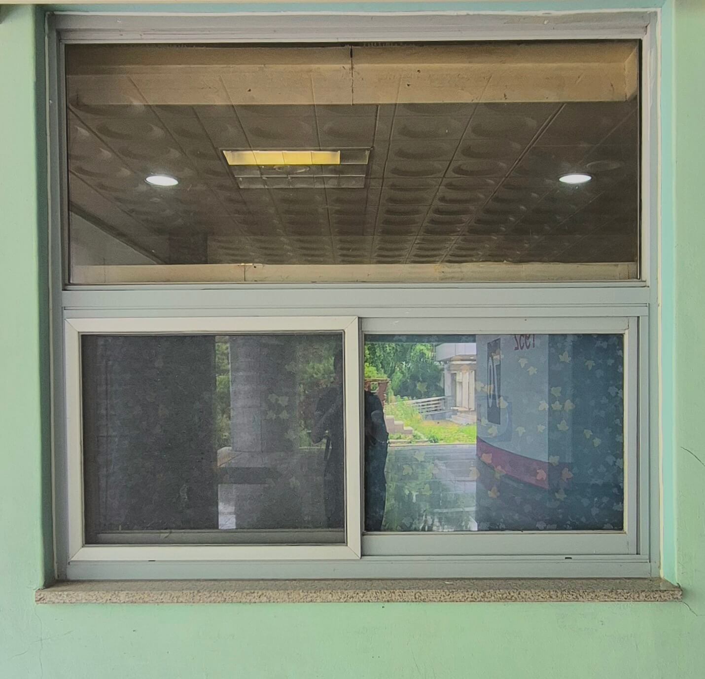 건축관 창문,민트색 벽 위로 흰 창틀로 된 직사각형 창문이 있다. 위쪽에 긴 직사각형 창문이 하나 있고, 그 아래에 동일한 크기의 창문 두 개가 나란히 붙어있는 형태이다..